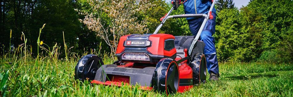 Person mäht Rasen mit Rasenmäher